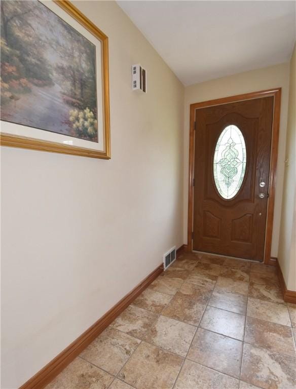 foyer entrance featuring lofted ceiling, baseboards, and visible vents