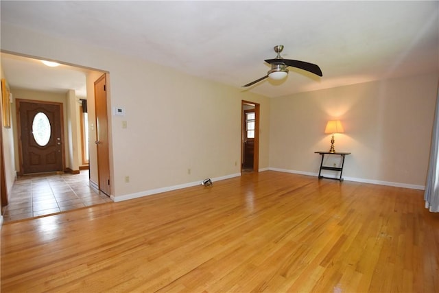 unfurnished living room with light wood-type flooring, a ceiling fan, and baseboards