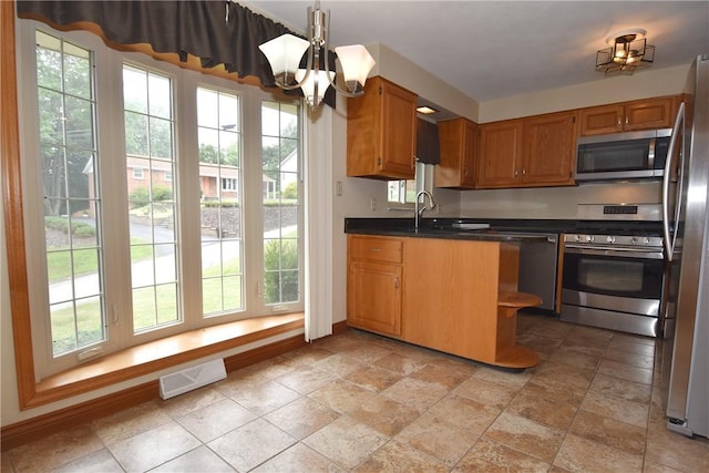 kitchen featuring visible vents, dark countertops, appliances with stainless steel finishes, brown cabinets, and a sink