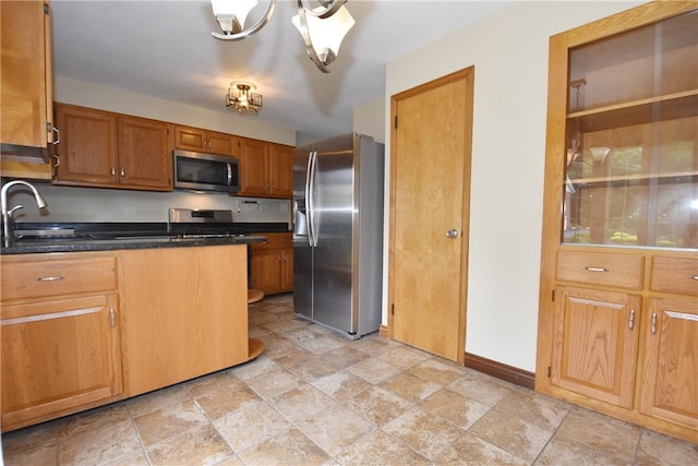 kitchen featuring stainless steel appliances, dark stone countertops, an inviting chandelier, light tile floors, and sink