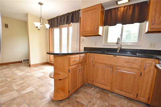 kitchen with pendant lighting, an inviting chandelier, brown cabinetry, a sink, and a peninsula