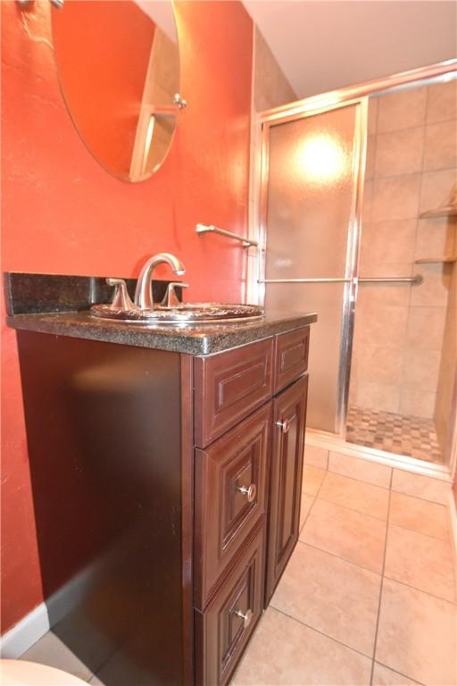 bathroom featuring tile floors, walk in shower, toilet, and vanity