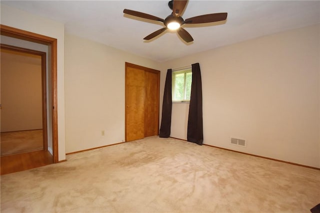 unfurnished bedroom featuring light colored carpet, a closet, visible vents, and baseboards