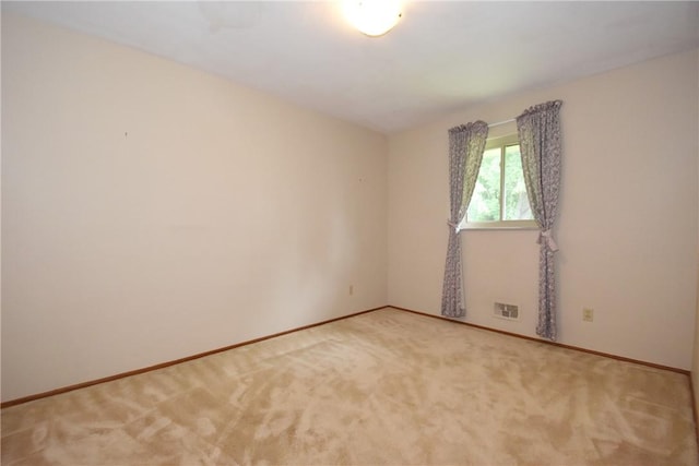 spare room featuring light colored carpet, visible vents, and baseboards