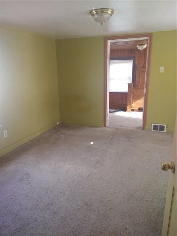 spare room with carpet flooring, baseboards, and visible vents