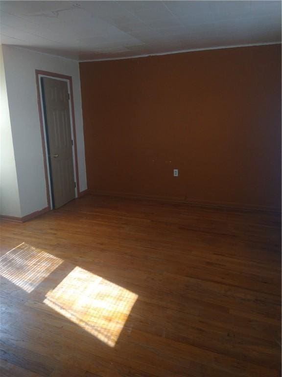 empty room with baseboards and wood finished floors