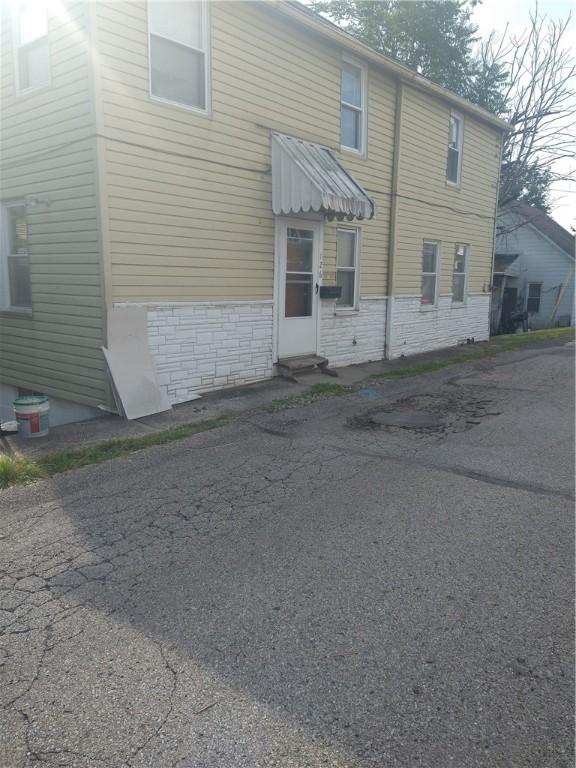 rear view of property featuring aphalt driveway, stone siding, and entry steps