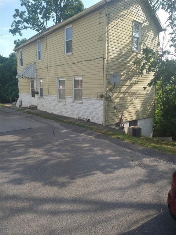 view of property exterior with stone siding and central AC