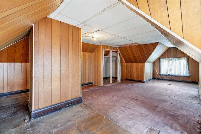 bonus room with wooden walls and lofted ceiling