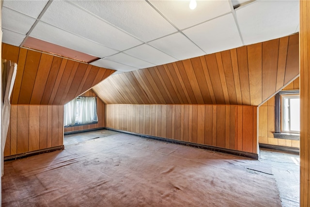 bonus room with wooden walls and vaulted ceiling