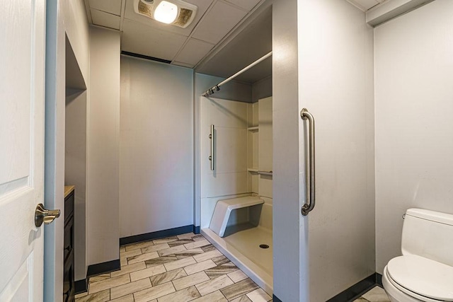 bathroom with a paneled ceiling, a shower, vanity, and toilet