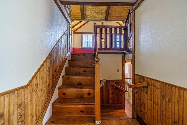 staircase with wood-type flooring and wooden walls