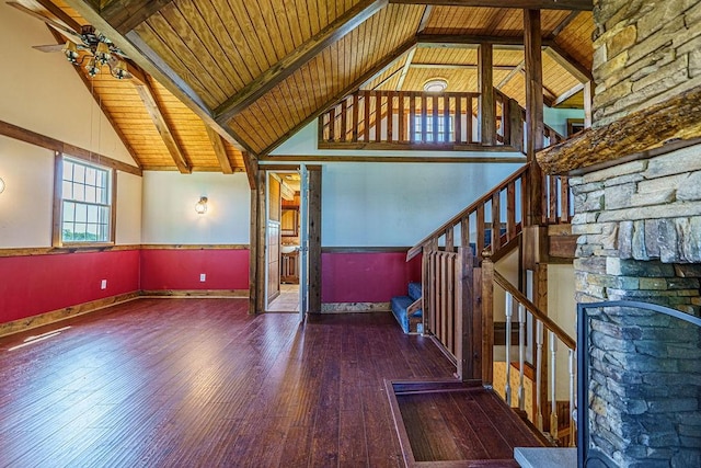 unfurnished living room featuring beamed ceiling, dark hardwood / wood-style floors, a fireplace, and wood ceiling