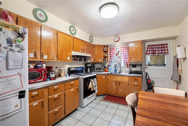 kitchen with refrigerator, light tile patterned flooring, sink, and white range with gas cooktop