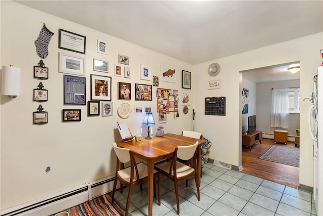 tiled dining space with a baseboard heating unit