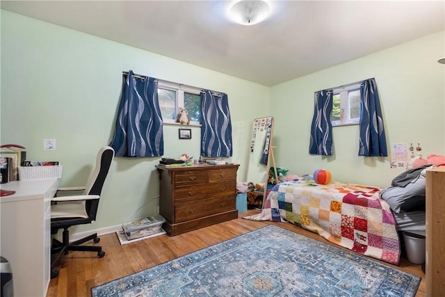 bedroom with hardwood / wood-style flooring and multiple windows