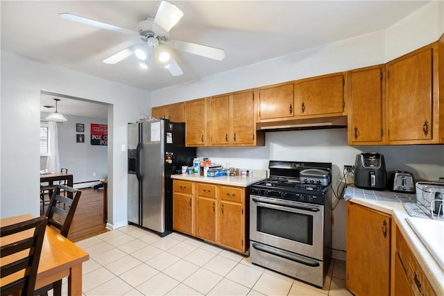 kitchen with ceiling fan, stainless steel appliances, a baseboard heating unit, pendant lighting, and light tile patterned flooring