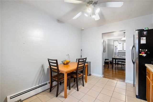 tiled dining space with ceiling fan and a baseboard radiator