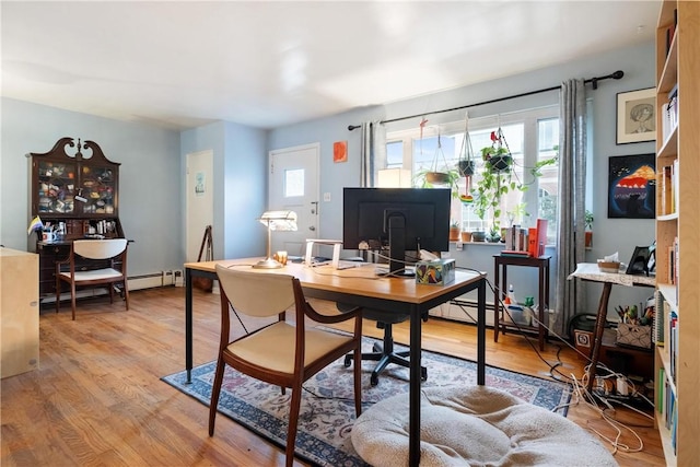 office space with light wood-type flooring and a baseboard heating unit