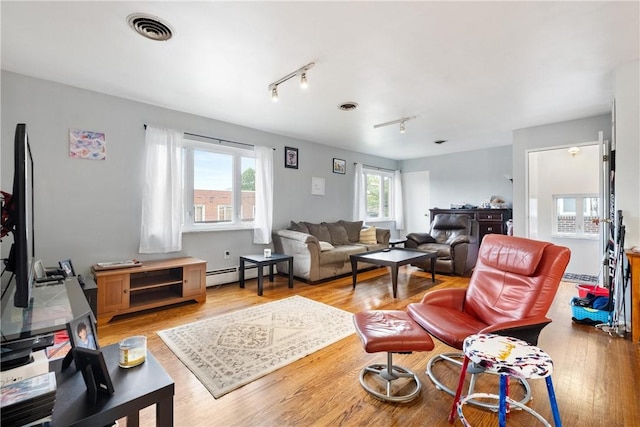 living room featuring baseboard heating, light hardwood / wood-style floors, and track lighting