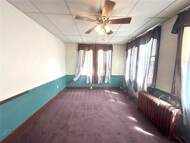 spare room with radiator, carpet flooring, a paneled ceiling, and ceiling fan