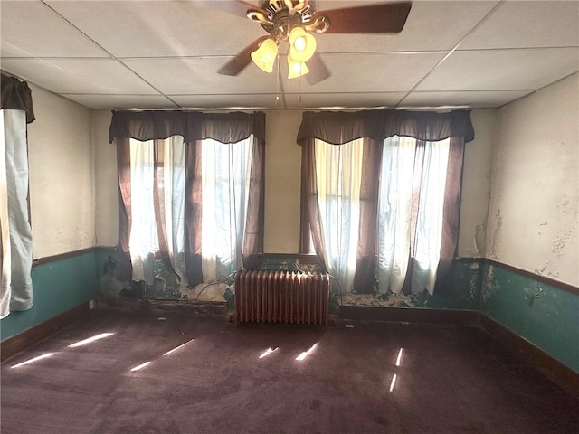 unfurnished room with a paneled ceiling, plenty of natural light, ceiling fan, and radiator heating unit