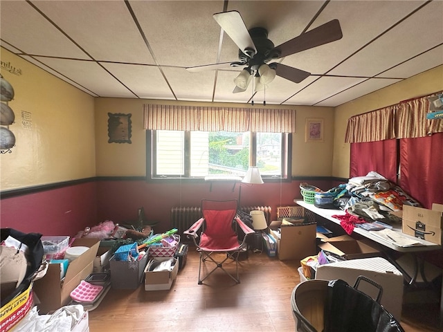 miscellaneous room featuring hardwood / wood-style floors, ceiling fan, radiator heating unit, and a paneled ceiling