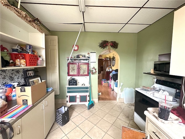 kitchen with white electric range oven, light tile flooring, and a drop ceiling