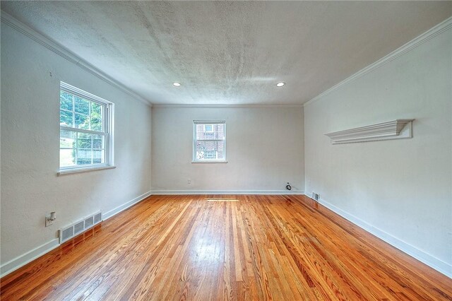 unfurnished room featuring ornamental molding, a textured ceiling, and light wood-type flooring