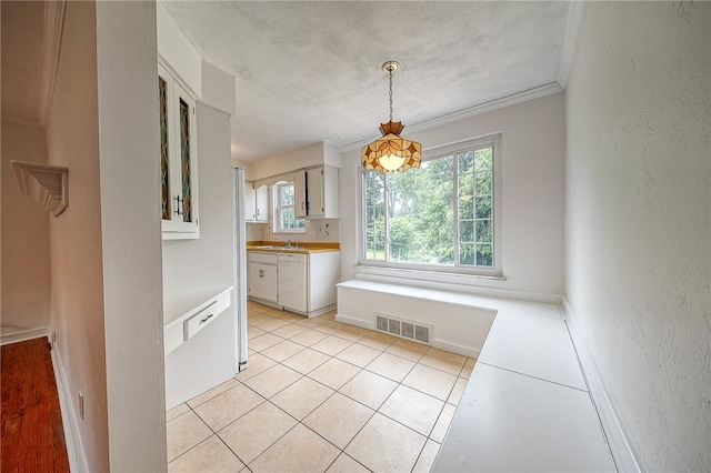 interior space featuring sink, a textured ceiling, ornamental molding, and light tile patterned floors