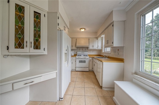 kitchen featuring premium range hood, decorative backsplash, a healthy amount of sunlight, and white appliances