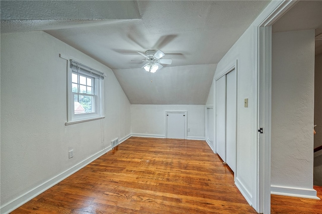 bonus room with lofted ceiling, hardwood / wood-style floors, a textured ceiling, and ceiling fan