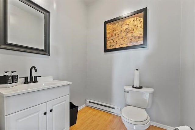 bathroom with wood-type flooring, baseboard heating, vanity, and toilet