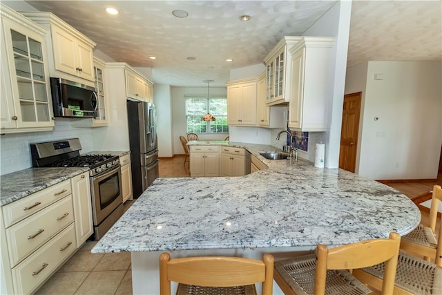 kitchen with a breakfast bar, decorative backsplash, stainless steel appliances, and decorative light fixtures