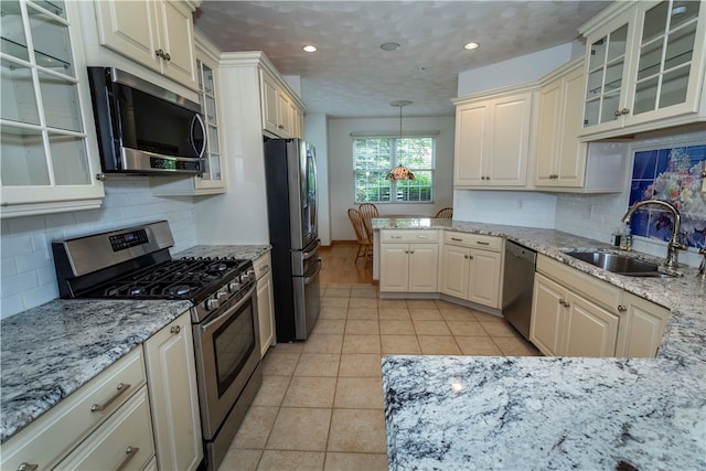 kitchen with sink, tasteful backsplash, decorative light fixtures, light stone counters, and stainless steel appliances