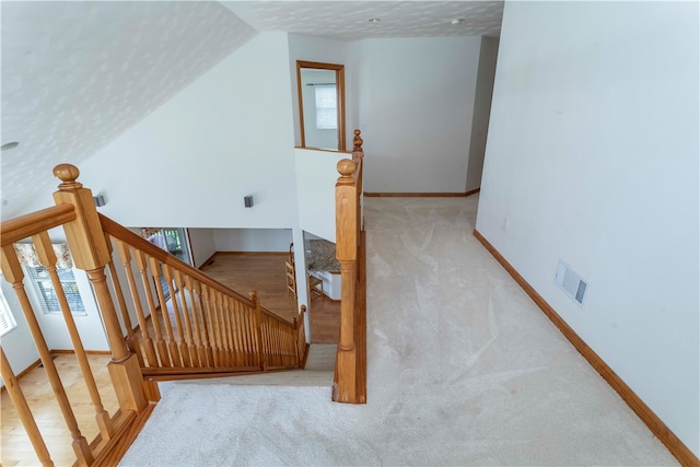 staircase with carpet, a textured ceiling, vaulted ceiling, and plenty of natural light