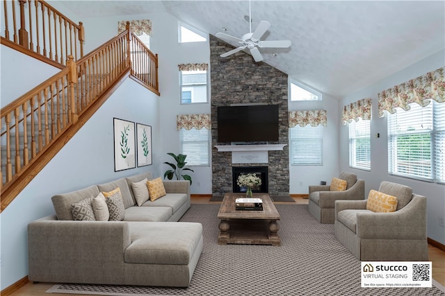 living room with a fireplace, hardwood / wood-style flooring, high vaulted ceiling, and ceiling fan