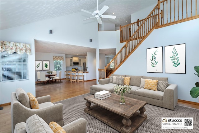 living room featuring hardwood / wood-style floors, ceiling fan, a towering ceiling, and a textured ceiling