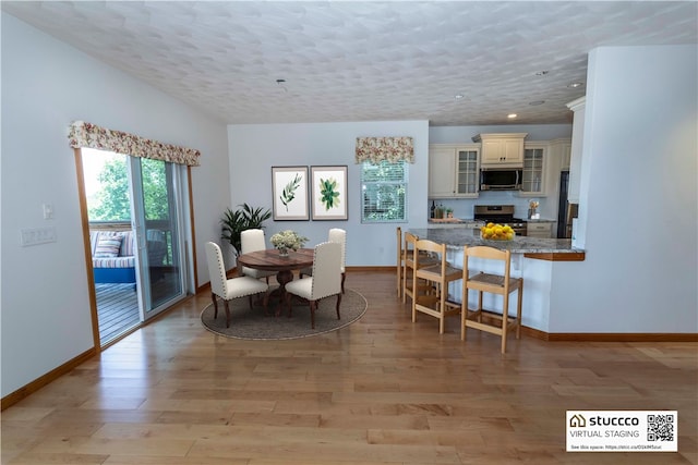 dining area with light hardwood / wood-style floors and a textured ceiling