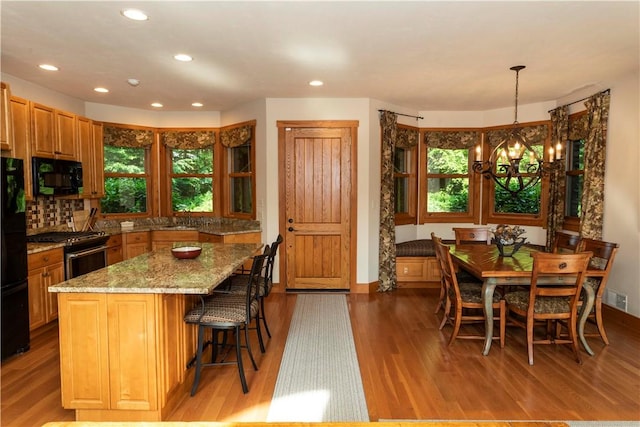 kitchen featuring black appliances, plenty of natural light, hardwood / wood-style floors, and decorative light fixtures