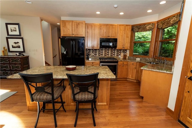 kitchen featuring a center island, sink, light hardwood / wood-style floors, and black appliances