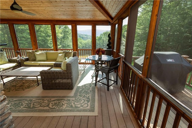 sunroom featuring lofted ceiling, ceiling fan, and wooden ceiling