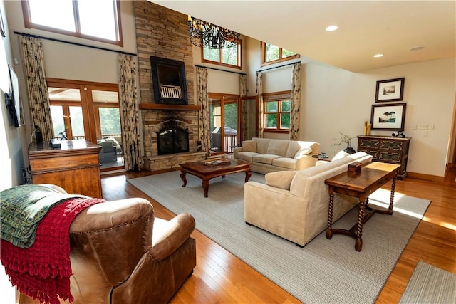 living room featuring a notable chandelier, plenty of natural light, wood-type flooring, and a fireplace