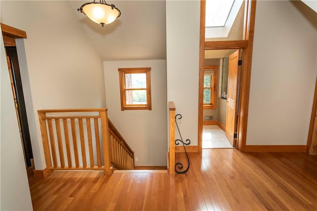 interior space with a skylight, high vaulted ceiling, and light hardwood / wood-style flooring