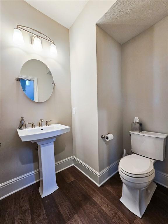 bathroom featuring wood-type flooring, a textured ceiling, and toilet