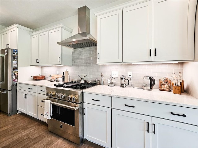 kitchen with white cabinetry, light stone countertops, wall chimney exhaust hood, tasteful backsplash, and appliances with stainless steel finishes