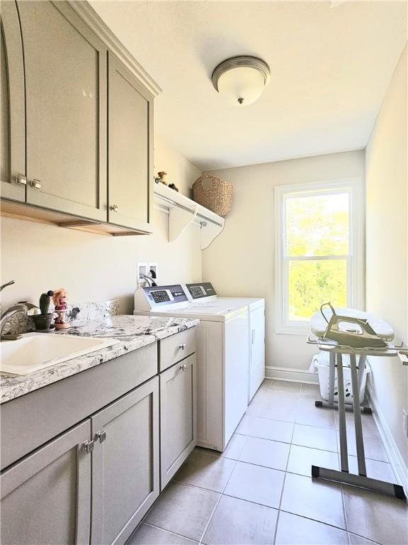 laundry room featuring cabinets, light tile patterned floors, washer and clothes dryer, and sink