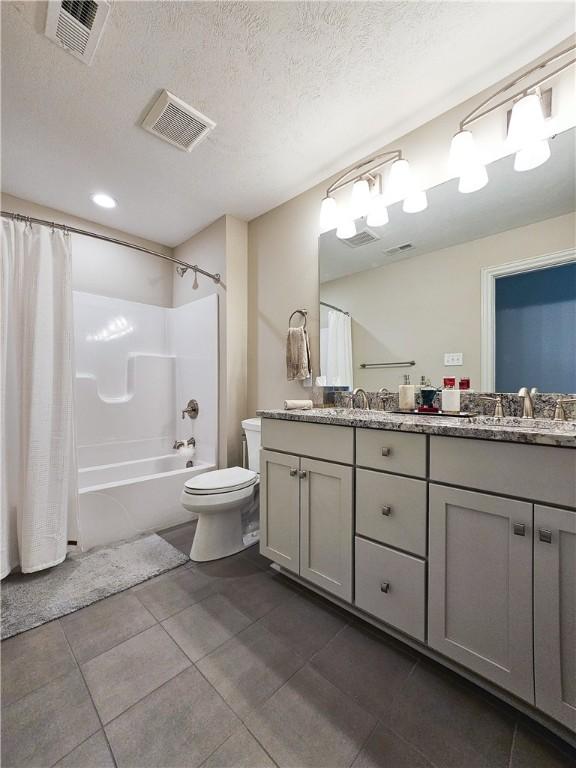 full bathroom featuring vanity, shower / tub combo, a textured ceiling, and toilet