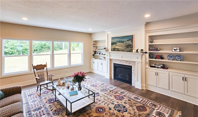 living room with built in shelves, dark hardwood / wood-style floors, and a textured ceiling