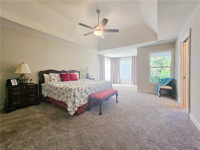 bedroom with a raised ceiling, ceiling fan, and carpet flooring